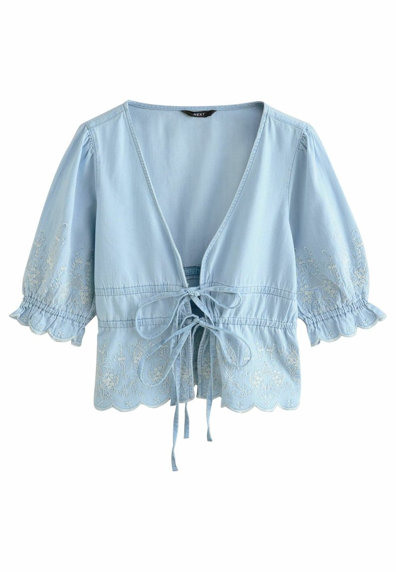 Lys blå bluse med puffede ærmer, V-halsudskæring, detaljer med frontknude og delikat hvid broderi langs kanten og ærmerne.
