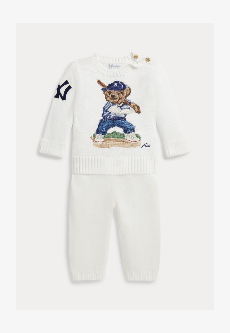 Conjunto de bebé blanco de punto con mangas largas, con un oso con equipo de béisbol bordado en el frente y un logo de NY en azul marino en la manga.
