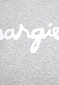 Ljust grått tyg med ordet "margie" i stora, vita, snirkliga bokstäver över mitten, vilket framhäver en avslappnad, trendig design.