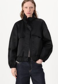 Black bomber jacket with a high collar, elastic cuffs, and a drawstring hem. Features two front pockets and a smooth, glossy texture.
