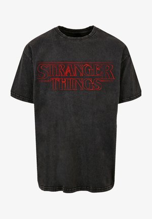 Schwarzes Baumwoll-T-Shirt mit dem "STRANGER THINGS"-Logo in kräftigem Rot. Kurze Ärmel, Rundhalsausschnitt, leicht abgenutzte Optik.