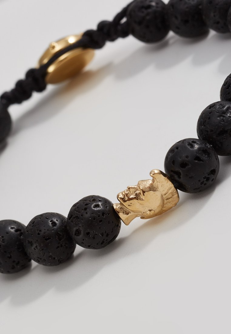 Schwarzes Lavastein-Armband mit einem goldenen Akzentperle in Form eines Kopfes, mit einer strukturierten matten Oberfläche und einem sicheren Verschluss.