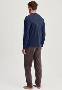 Navy lange mouwtop gecombineerd met gestreepte pyjamabroek met geometrische ontwerpen in rood en marineblauw, ontworpen voor comfortabel dragen.