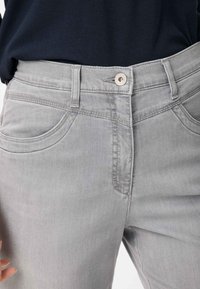 Grå denim jeans med en tætsiddende pasform, fem lommer og en glat tekstur, med en frontlukning med knap og kontraststing.