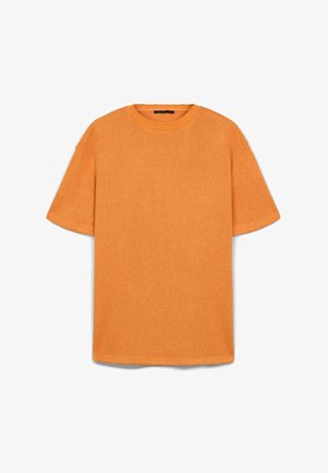 T-shirt à manches courtes, ample, en tissu tricoté texturé de couleur orange vif, avec un col rond et un ourlet droit.