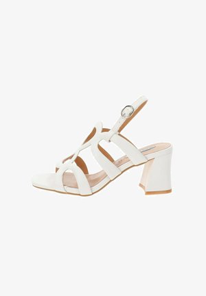 Sandal bianca con tacco a blocco, caratterizzata da un design con cinturini e fibbia alla caviglia. Il materiale liscio e la soletta testurizzata offrono comfort.