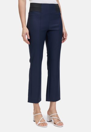 Marineblaue maßgeschneiderte Hose mit einem hohen schwarzen Bund, schmaler Passform und knöchellanger Schnittführung, die dezente Nahtdetails und eine glatte Textur aufweist.