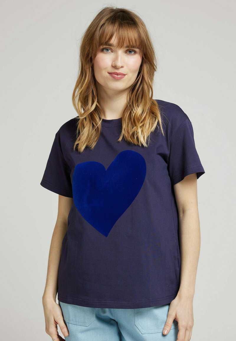 T-shirt en coton bleu marine à manches courtes, avec un grand design de cœur lisse et foncé à l'avant. Style classique à col rond.