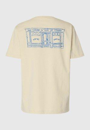 Kreemikas valge T-särk sinise joonistusega kauplusefassaadist, millel on silt "HOTEL AMOUR" ja prantsuskeelne tekst ukse kohal ülemisel seljal.