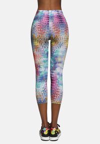 Legginsy do kolan w wielokolorowym abstrakcyjnym wzorze z wyrazistymi odcieniami różu, fioletu, niebieskiego i pomarańczowego, o gładkiej fakturze.