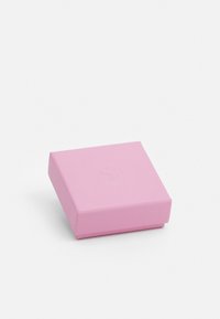 Självrande rosa låda i fyrkantig form, tillverkad av strukturerat papper, med en subtil präglad logotyp på toppen. Stängd design utan synlig hårdvara eller detaljer.