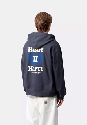Sudadera de color navy con un gran gráfico en blanco y azul que dice "Heart II Hartt" en la parte posterior. Cuenta con un clásico bolsillo tipo canguro y capucha con cordón.