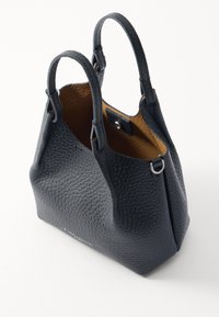 Black leather handbag with a textured exterior, rounded handles, and a contrasting tan interior. Features a snap closure and silver hardware accents.