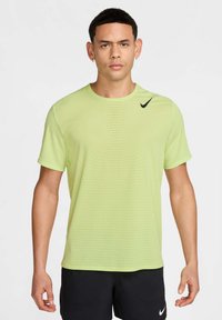 T-shirt de sport à manches courtes Nike en vert clair, avec un motif texturé et un logo noir contrastant sur la poitrine gauche.
