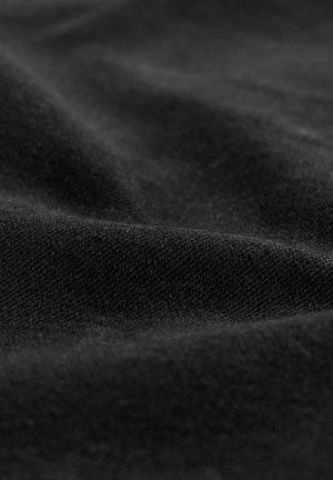 Schwarzer Stoff mit glatter Textur, der subtile Variationen in Webart und Glanz aufweist, in sanften, fließenden Falten angeordnet.