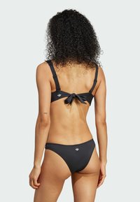 Černý bikini set s vrškem na zavazování, nastavitelnými ramínky a klasickými kalhotkami, vyrobený z hladkého, elastického materiálu.