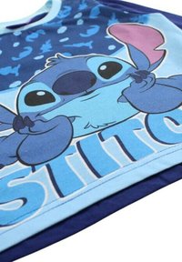 T-shirt bleu clair avec un personnage de dessin animé aux traits exagérés sur un fond bleu foncé, en tissu de coton doux.