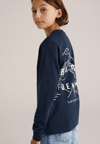 Námořnické tričko s dlouhým rukávem vyrobené z bavlny, s bílým grafikou hory a textem na zadní straně. Volný střih s kulatým výstřihem a manžetami.