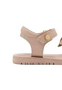 Sandalo rosa chiaro con una tomaia in pelle testurizzata, cinturino regolabile e una suola piatta in gomma con un motivo a zigzag per la presa.