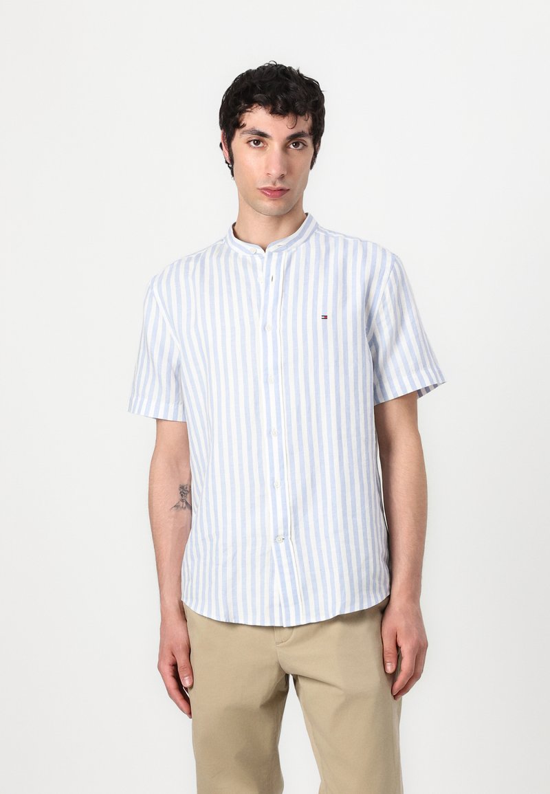 Camicia a maniche corte con bottoni, a strisce verticali blu chiaro e bianche, colletto alla coreana e dettagli del logo discreti sul petto.