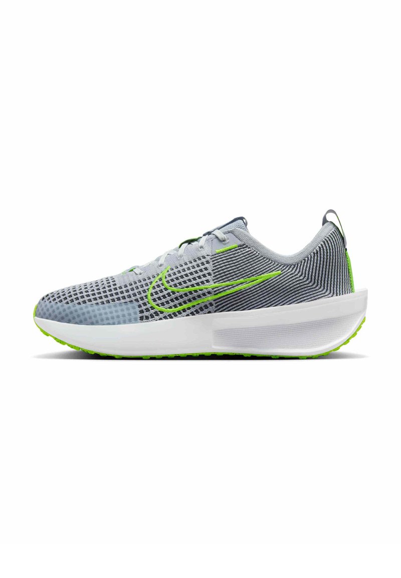 Zapatilla deportiva gris con parte superior de malla, acentos verdes y patrón texturizado. Cuenta con una suela blanca acolchada y un diseño de talón redondeado.