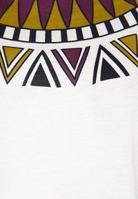 Biały materiał z geometrycznym wzorem trójkątów w kolorach musztardowym, burgundowym i czarnym, obramowanych serią czarno-białych linii.