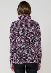 Pull en polaire à col haut, avec un motif moucheté multicolore dans les tons rose, blanc et noir. Manches longues et coupe décontractée.