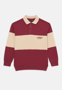 Langærmet polo i bordeaux og creme, med krave, frontlogo og ribbede manchetter. Fremstillet af textureret stof med kontrasterende farver.