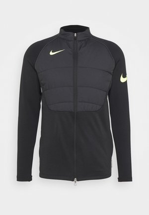 Czarna sportowa kurtka zapinana na zamek błyskawiczny z pikowanym przednim panelem i żółtymi logo Nike Swoosh na piersi oraz na lewym rękawie.