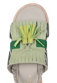 Sandalo verde in suede con dettagli in frange, una cinghia in tessuto verde e una suola color sabbia. Presenta un fiocco decorativo con accenti verdi.
