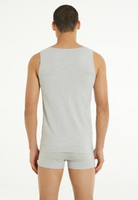 Szary bawełniany tank top o prostym kroju, z szerokimi wycięciami na ramiona i gładką teksturą, w zestawie z pasującymi szarymi szortami bokserskimi.