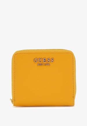 Kollane sünteetiline rahakott, millel on tõmblukuga sulgus, reljeefne "GUESS EST 1981" logo, sile tekstuur ja ristküliku kuju.