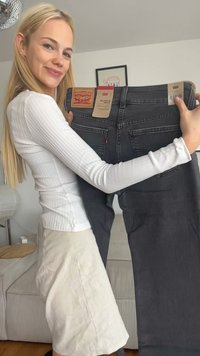 Jeans de denim cinza segurados, com um patch de marca de couro na parte de trás. O tecido tem uma textura suave e possui bolsos traseiros padrão.