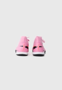 Scarpe sportive rosa con design alta, tessuto testurizzato, dettagli neri e suole bianche. Logo arancione sul tallone.
