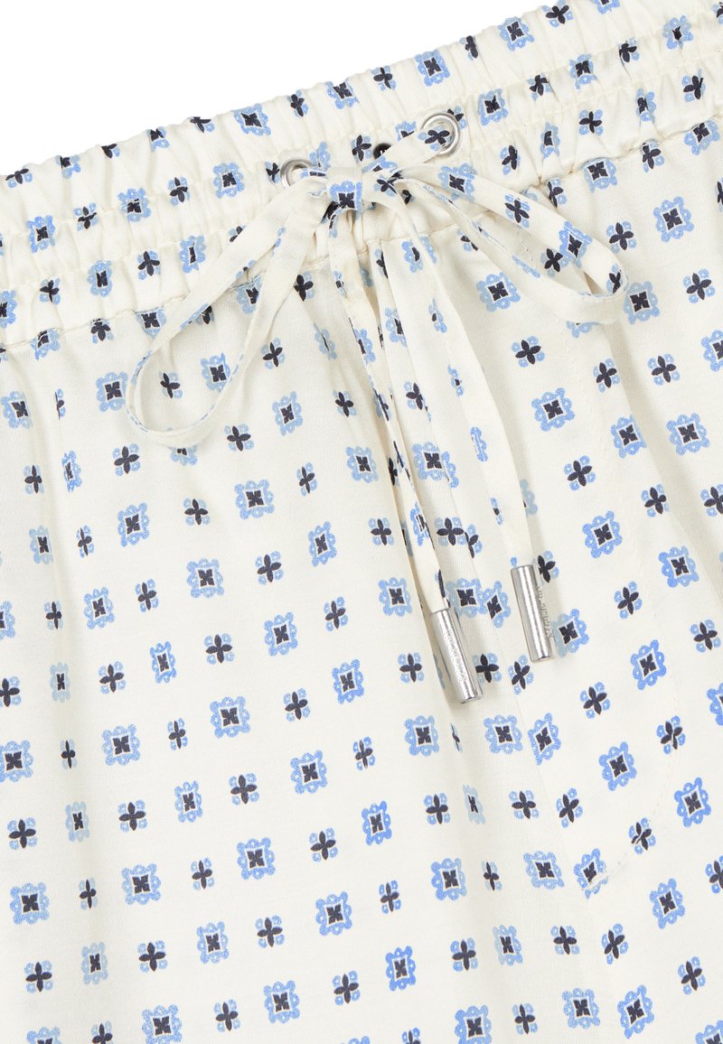 Cintura elástica con cordón atado en tela blanca con un pequeño patrón cuadrado floral azul y negro.