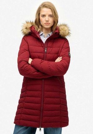 Abrigo acolchado burdeos con capucha de piel sintética, acolchado horizontal, cremallera frontal y bolsillos laterales. La tela es suave con un acabado mate.