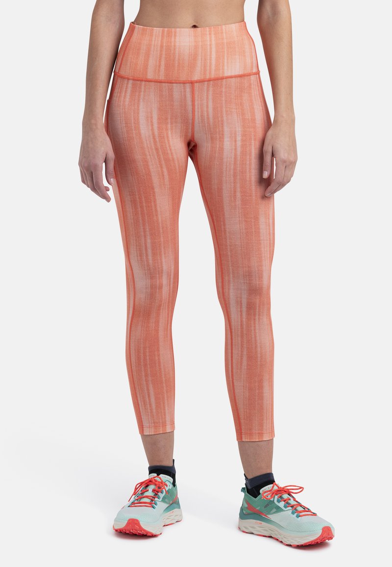 Orange stribede leggings med høj talje, lavet af et strækbart materiale, parret med lette, farverige løbesko.