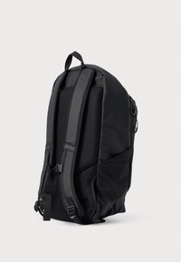 Melnā mugursoma ar mīkstu neilona apvalku, polsterētām siksnām, acs materiāla aizmugures paneli un rāvējslēdzējiem. Aprīkota ar sānu kabatām papildu uzglabāšanai.