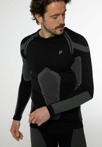 Schwarz langärmeliges Sportshirt mit grauen geometrischen Mustern, taillierter Passform und kontrastierenden strukturierten Akzenten an den Schultern und Ärmeln.