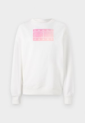 Balta sportinė megztinė su apvalia apykakle ir išklotais rankogaliais, dekoruota rožinės spalvos gradientu ir stačiakampiu logotipu, kuris skelbia "TOMMY JEANS" didžiosiomis raidėmis.