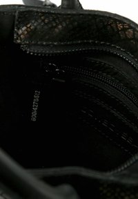 Borsa nera con un motivo testurizzato di pelle di serpente. Presenta più scomparti con zip e un rivestimento interno liscio.