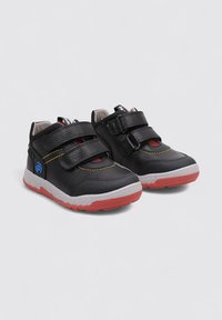 Chaussures synthétiques noires avec deux bandes Velcro, accents rouges et semelle texturée. Comprend un col rembourré pour le confort et la stabilité.