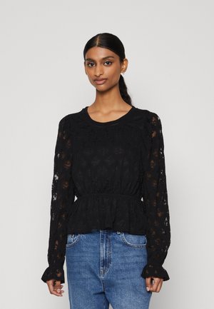 Black lace blouse with long, puffed sleeves, a round neckline, and a cinched waist. Paired with light blue jeans. Textured floral pattern.