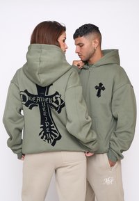 Felpe con cappuccio verde oliva con grafiche di croci nere; una ha una chiusura con zip anteriore e l'altra presenta un grande design sul retro; tessuto morbido e texturizzato.