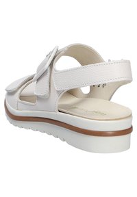 White leather sandal with hook-and-loop closure, curved design, cushioned footbed, and textured sole for grip; features open sides and back.