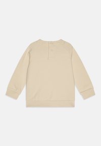 Sudadera de manga larga beige con cuello redondo, cierre de tres botones en la parte posterior y puños y dobladillo acanalados. Textura de tela suave.