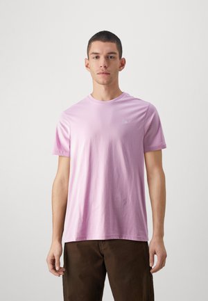 Camiseta de algodón de color rosa claro con mangas cortas y escote redondo. Presenta un pequeño y sutil logo en el pecho. Textura suave.