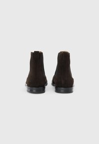 Bottines en daim marron avec des panneaux latéraux élastiques, une languette à l'arrière et des semelles en caoutchouc. Le design présente une finition lisse et un minimum de détails.