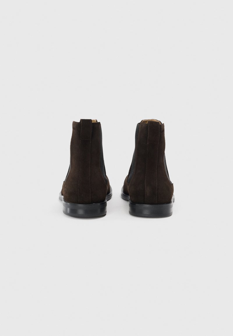 Braune Wildlederstiefeletten mit elastischen Seitenteilen, einer Zugschlaufe hinten und Gummisohlen. Das Design zeichnet sich durch eine glatte Oberfläche und minimale Details aus.