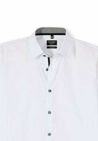 Weißes Hemd mit super schmaler Passform. Verfügt über einen kontrastierenden schwarzen Krageninneren und schwarze Knöpfe entlang der Vorderleiste. Weicher Stoff.